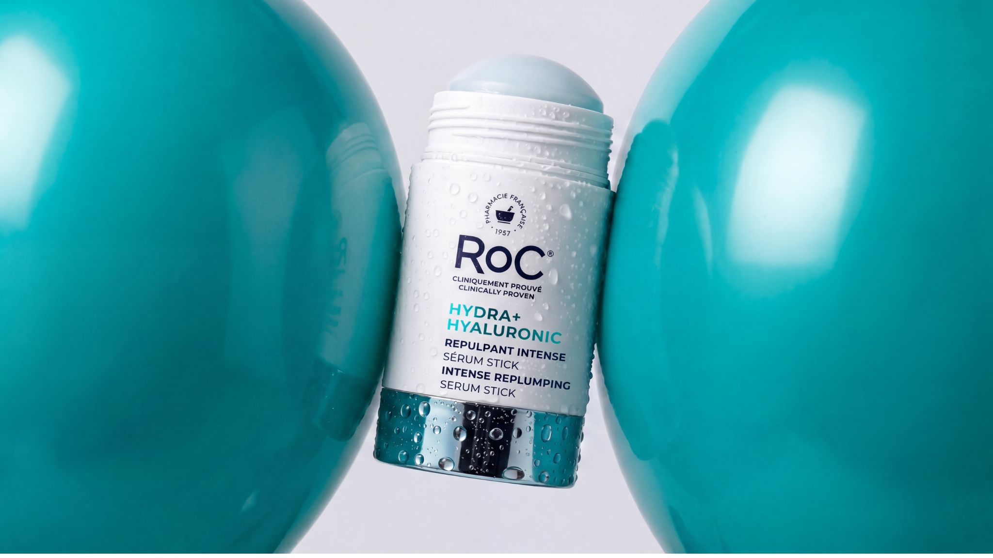 Envase de RoC Hydra+ Hyaluronic Serum Stick con gotas de agua sobre fondo azul y blanco.