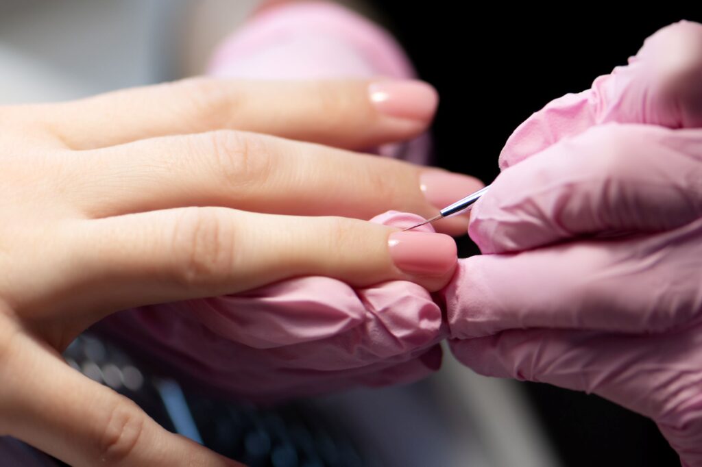 Detalle de manicurista dando forma a la estructura de gel con pincel de precisión.