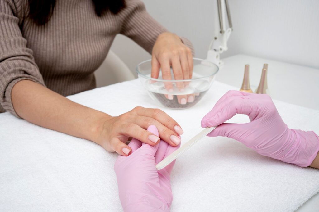 Manicurista aplicando gel autonivelante sobre la uña con pincel de precisión.