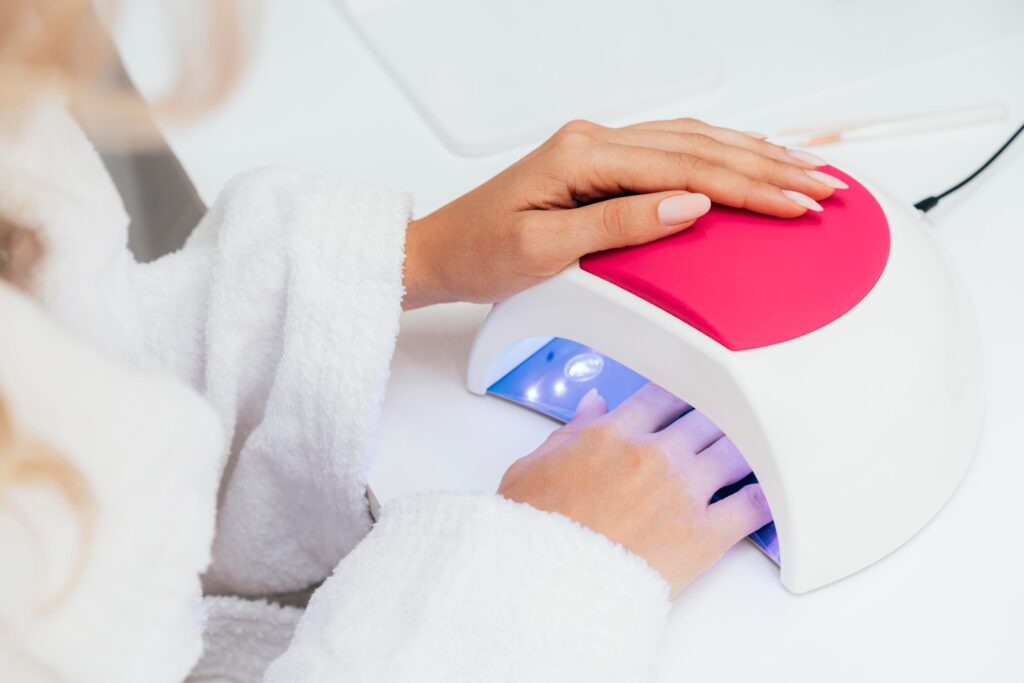 Cliente introduciendo la mano en lámpara UV LED durante el proceso de manicura de gel.