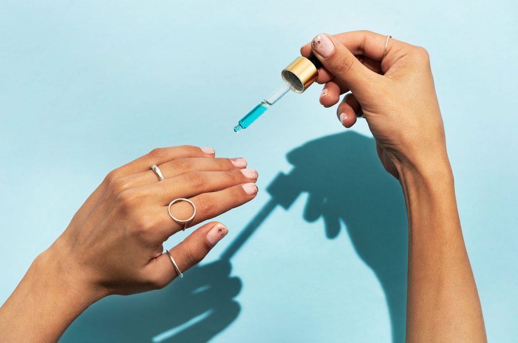 Aplicación de pipeta con aceite hidratante para cutículas en manicura de gel.
